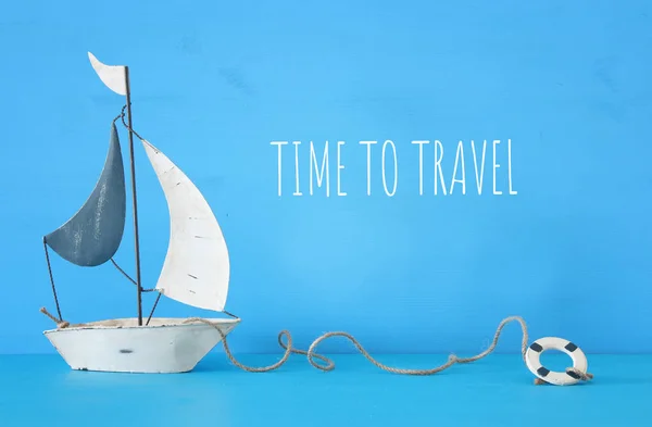 Concetto nautico con barca a vela decorativa bianca su tavola di legno blu e testo: tempo per viaggiare . — Foto Stock