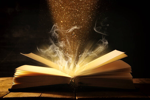 изображение открытой антикварной книги над деревянным столом
.