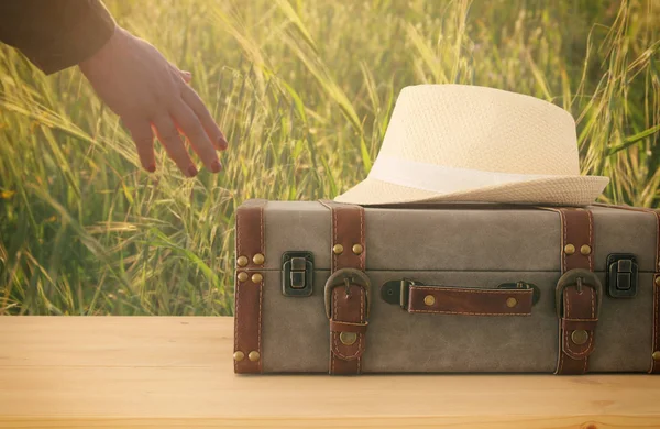 Reiziger vintage bagage en fedora hoed over houten tafel. vakantie en vakantie concept. — Stockfoto