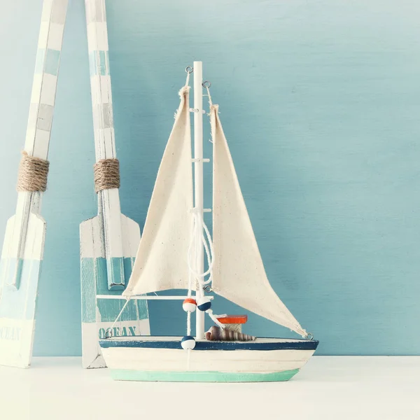 Conceito náutico com veleiro decorativo branco e remos de madeira sobre fundo azul . — Fotografia de Stock