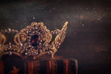 Tahta masanın üzerindeki güzel kraliçe ve kral tacının gösterişsiz görüntüsü. Eski model filtrelenmiş. fantezi ortaçağ dönemi.