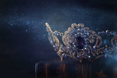 Tahta masanın üzerindeki güzel kraliçe ve kral tacının gösterişsiz görüntüsü. Eski model filtrelenmiş. fantezi ortaçağ dönemi.