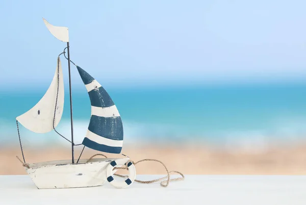 Nautical concept with sail boat over white wooden table infront of sea background. — Stock Photo, Image