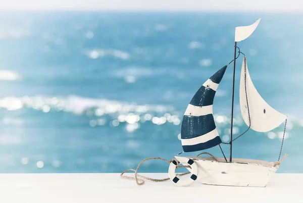 Concetto nautico con barca a vela su tavolo di legno bianco davanti al fondo del mare . — Foto Stock