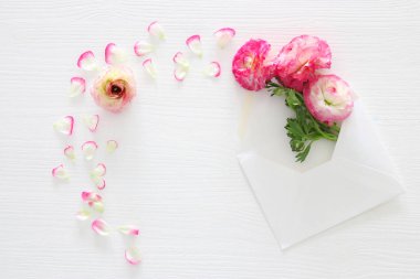 Zarf ile hassas pastel pembe güzel çiçek aranjman beyaz ahşap zemin üzerinde görüntü. Düz yatıyordu, en iyi görünümü.