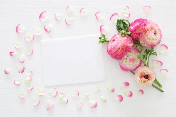 Bild av kuvert med delikat pastell rosa vackra blommor arrangemang över vit trä bakgrund. Platt lekmanna, top view. — Stockfoto
