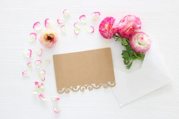 Image of envelope with delicate pastel pink beautiful flowers arrangement over white wooden background. Flat lay, top view. — Stock Photo, Image