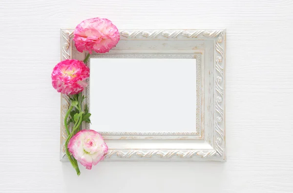 Image de délicat arrangement de belles fleurs rose pastel et cadre photo vintage vide sur fond blanc en bois. Couché à plat, vue de dessus. Pour la photographie montage maquette . — Photo