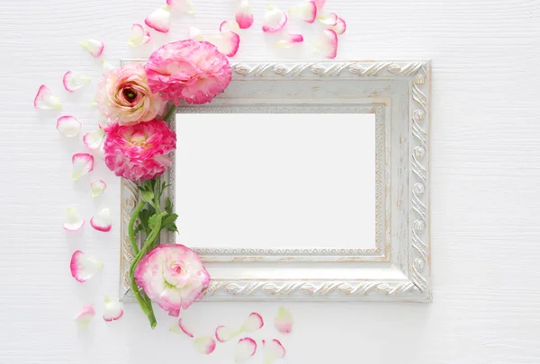 Image de délicat arrangement de belles fleurs rose pastel et cadre photo vintage vide sur fond blanc en bois. Couché à plat, vue de dessus. Pour la photographie montage maquette . — Photo