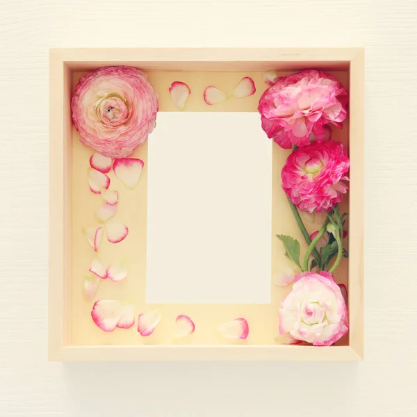 Imagen de delicada pastel rosa hermoso arreglo de flores y marco de fotos vintage vacío sobre fondo de madera blanca. Asiento plano, vista superior. Para montaje de maquetas fotográficas . — Foto de Stock