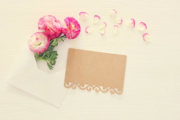 흰색 나무 배경 위에 섬세 한 파스텔 핑크 아름 다운 꽃 배열 가진 봉투의 이미지. 평면 위치, 최고 볼 수 있습니다. 빈티지 필터링. — 스톡 사진