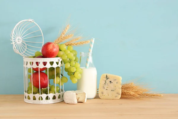 Изображение фруктов и сыра в декоративной корзине над деревянным столом . — стоковое фото
