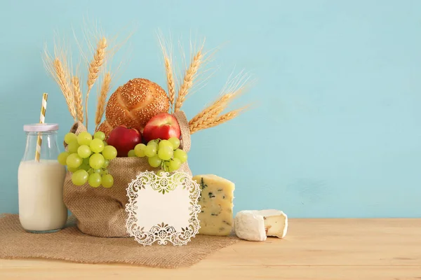 Изображение фруктов, хлеба и сыра в корзине над деревянным столом . — стоковое фото