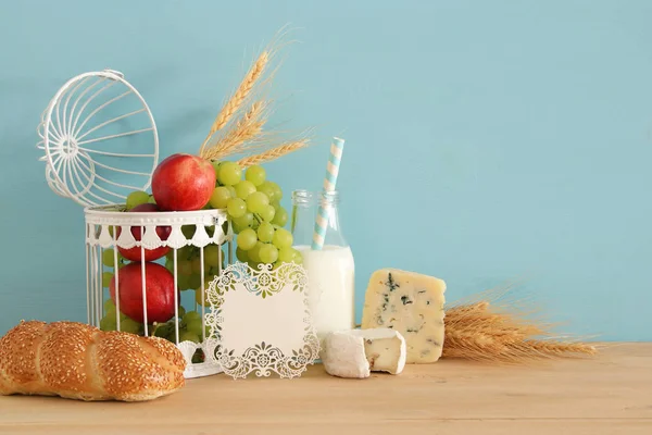 Imagem de frutas, pão e queijo em cesta decorativa sobre mesa de madeira . — Fotografia de Stock