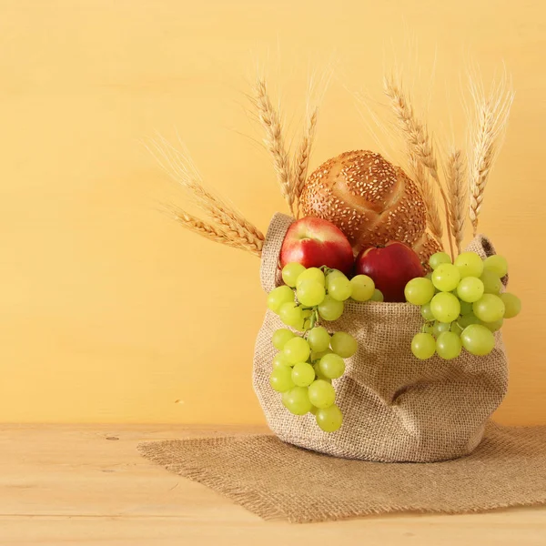 Immagine di frutta e pane nel cesto sopra la tavola di legno . — Foto Stock