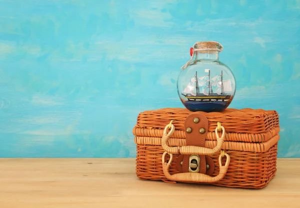 Námořních koncept obrázek s plachetnice v láhvi a starý proutěný kufr box dřevěný stůl. Selektivní fokus — Stock fotografie