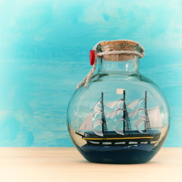 Námořních koncept obrázek s plachetnice v láhvi přes dřevěný stůl. Selektivní fokus. — Stock fotografie