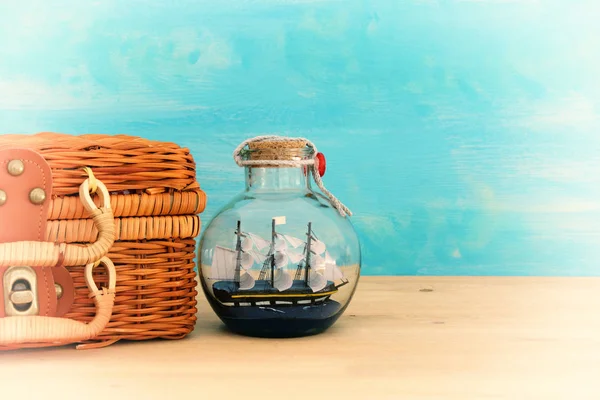 Yelkende şişesi ve eski hasır çanta kutusunun üzerine ahşap masa ile deniz kavramı görüntü. Seçici odak. — Stok fotoğraf
