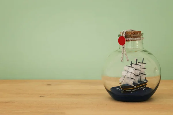 Nautical concept image with sail boat in the bottle over wooden table. Selective focus — Stock Photo, Image