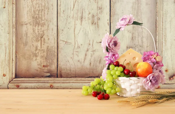 Image de fruits et fromage dans un panier décoratif avec des fleurs sur une table en bois. Symboles de vacances juives - Shavuot . — Photo