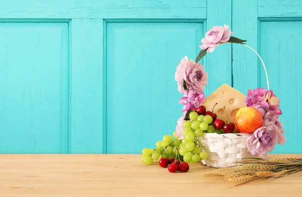 Afbeelding van fruit en kaas in de decoratieve mand met bloemen over houten tafel. Symbolen van Joodse vakantie - Sjavoeot (Wekenfeest). — Stockfoto