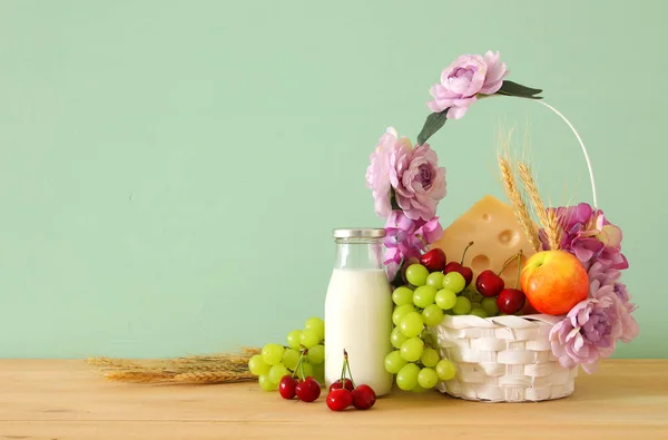 Imagen de frutas y queso en cesta decorativa con flores sobre mesa de madera. Símbolos de la fiesta judía - Shavuot . —  Fotos de Stock