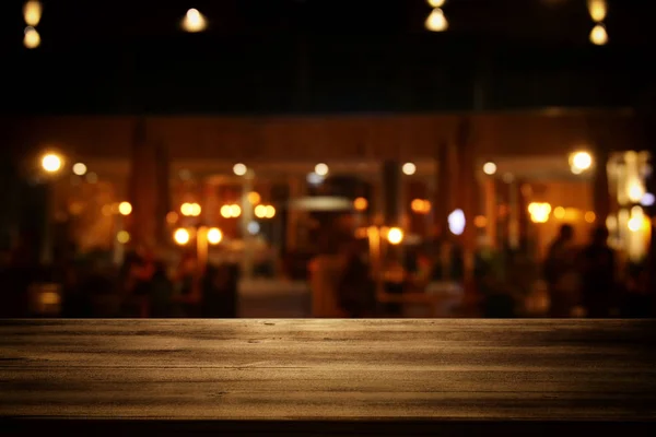 Obrázek dřevěný stůl před restaurace abstraktní rozmazané světla pozadí. — Stock fotografie