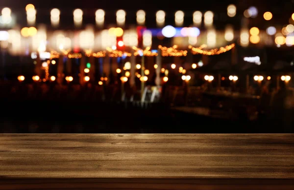 Εικόνας του ξύλινο τραπέζι μπροστά από αφηρημένη θολή εστιατόριο φώτα φόντο. — Φωτογραφία Αρχείου