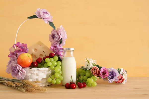 Imagen de frutas y queso en cesta decorativa con flores sobre mesa de madera. Símbolos de la fiesta judía - Shavuot . — Foto de Stock