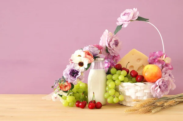 Imagem de frutas e queijo em cesta decorativa com flores sobre mesa de madeira. Símbolos de férias judaicas - Shavuot . — Fotografia de Stock