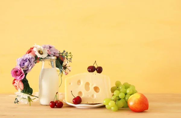 フルーツとチーズの木製のテーブルの上の花で装飾的なバスケットのイメージ。ユダヤ人の休日 - シャブオットのシンボル. — ストック写真