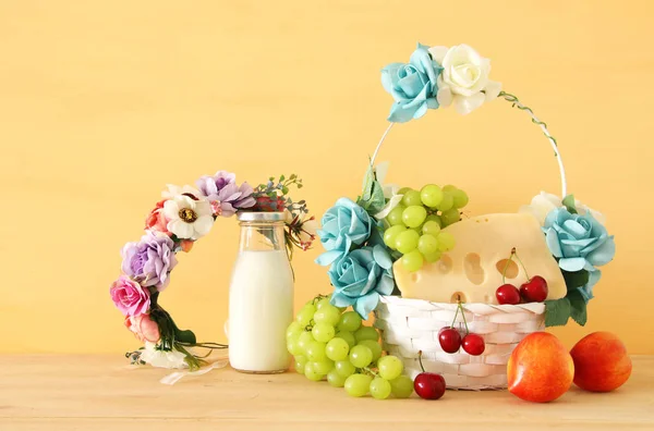 Imagen de frutas y queso en cesta decorativa con flores sobre mesa de madera. Símbolos de la fiesta judía - Shavuot . —  Fotos de Stock