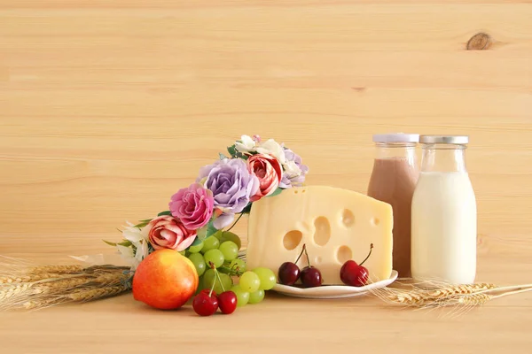 フルーツとチーズの木製のテーブルの上の花で装飾的なバスケットのイメージ。ユダヤ人の休日 - シャブオットのシンボル. — ストック写真