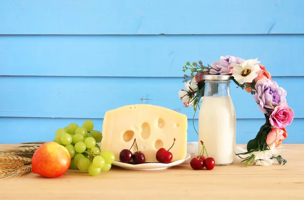 Εικόνα του φρούτα και τυρί σε διακοσμητικό καλάθι με λουλούδια πάνω από το ξύλινο τραπέζι. Σύμβολα της εβραϊκής διακοπές - Σαβότ. — Φωτογραφία Αρχείου