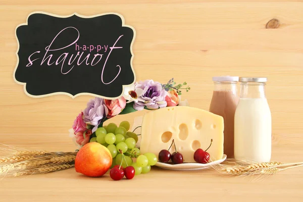 Image of fruits and cheese in decorative basket with flowers over wooden table. Symbols of jewish holiday - Shavuot. — Stock Photo, Image