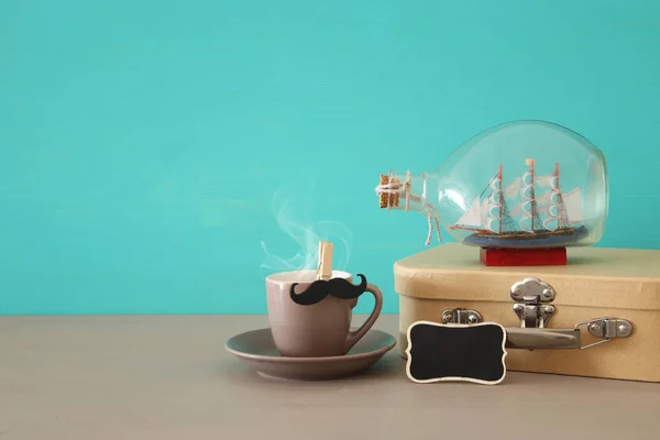 杯子的咖啡, 旧的箱子和小船在木桌的瓶子的形象。父亲节概念. — 图库照片
