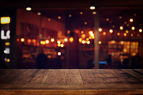 Image of wooden table in front of abstract blurred restaurant lights background. — Stock Photo, Image