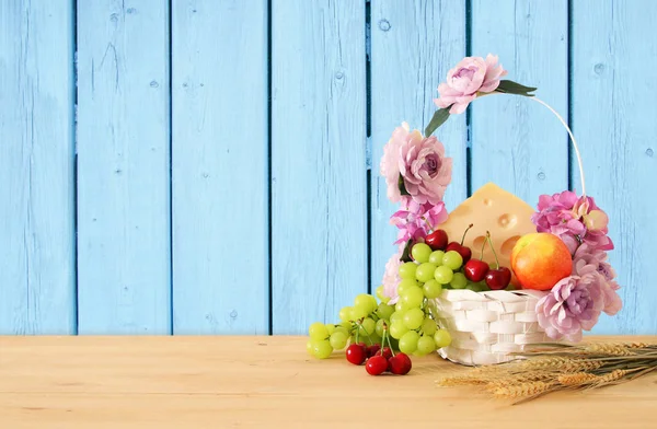 Зображення фруктів і сиру в декоративних кошик з квітами над дерев'яний стіл. Символи єврейське свято - Шавуот. — стокове фото