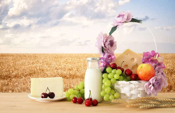 Image de fruits et fromage dans un panier décoratif avec des fleurs sur une table en bois. Symboles de vacances juives - Shavuot . — Photo