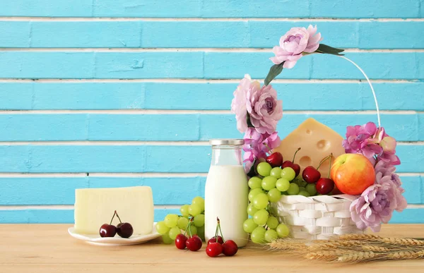 Imagem de frutas e queijo em cesta decorativa com flores sobre mesa de madeira. Símbolos de férias judaicas - Shavuot . — Fotografia de Stock