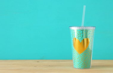 minimalizm kavramı. Nane plastik bardak soda ya da saman ahşap masa üzerinde içme ile soğuk içecek için altın kalp dekorasyonu ile.