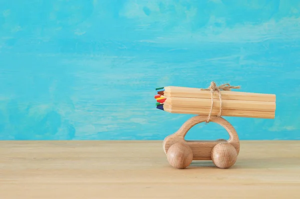 Torniamo al concetto di scuola. Macchina giocattolo in legno con matite colorate sul tetto . — Foto Stock