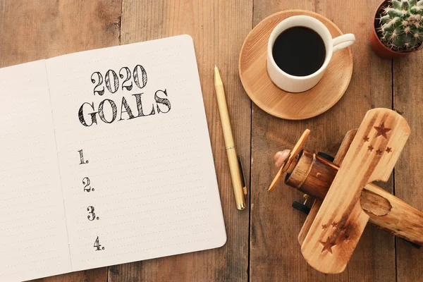 Zakelijk concept van top view 2020 doelen lijst met notebook, kopje koffie en oud vliegtuig speelgoed over houten bureau — Stockfoto