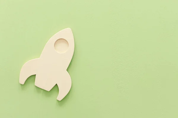 wooden rocket on a green pastel background