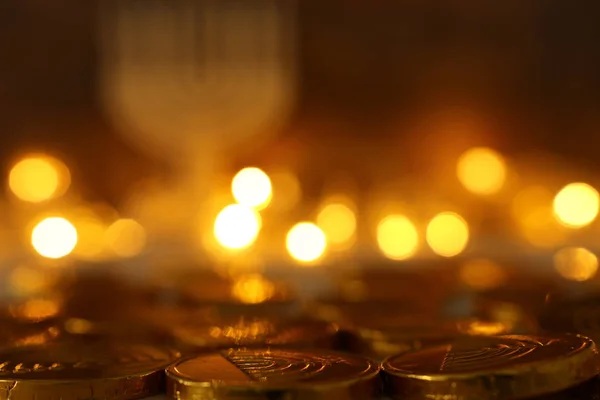 Concepto religioso de fiesta judía Hanukkah con monedas de chocolate (peonza) sobre mesa de madera y fondo de luces bokeh — Foto de Stock