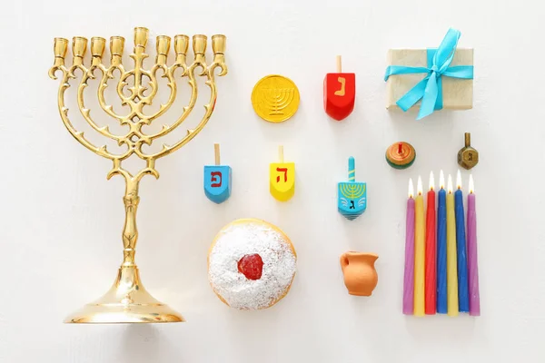 犹太假日光明节的宗教形象。光明节背景与传统的烛光，旋转顶部和甜甜圈在木制的白色背景。 顶视图,平铺 — 图库照片