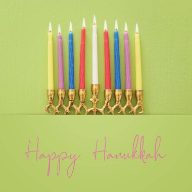 Religion image of jewish holiday Hanukkah background with menorah (traditional candelabra) and candles over pastel green background. top view, flat lay clipart