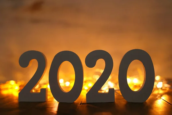 Фон 2020 року щасливий новорічний концепт, дерев'яні номери над столом і золоті фонові світильники — стокове фото
