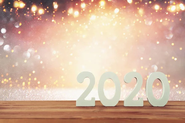 Фон 2020 року щасливий новорічний концепт, дерев'яні номери над столом та блискучий фон — стокове фото