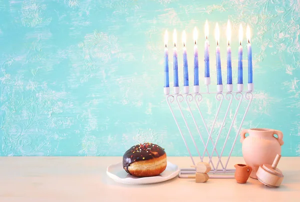 Θρησκευτική εικόνα της εβραϊκής διακοπές Hanukkah φόντο με μενόρα (παραδοσιακά κηροπήγια), περιστρεφόμενη κορυφή και ντόνατ πάνω από παστέλ φόντο — Φωτογραφία Αρχείου